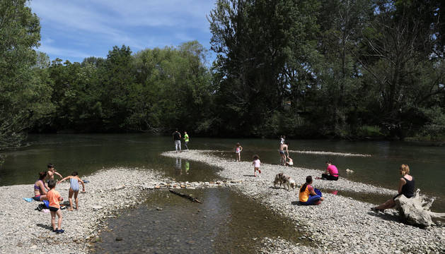 Disfrutar del sol e incluso refrescarse a la orilla del río Arga alivió del calor a decenas de personas.