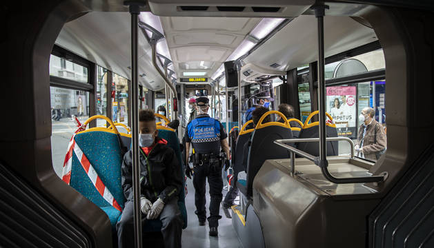Dos policías municipales vigilan que la gente lleve mascarilla dentro del transporte público.