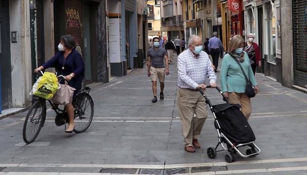 Varias personas cubiertas con mascarillas caminan por una calle del Casco Viejo de Pamplona.