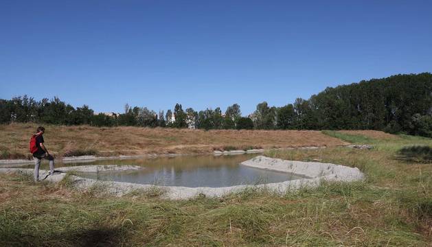 Foto de una persona observando la zona de agua embalsada dentro del meandro de Areacea, junto al río Arga en Huarte.