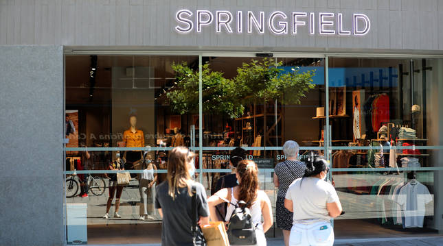 Un grupo de personas espera a la entrada de la tienda Springfield, en la avenida Carlos III.