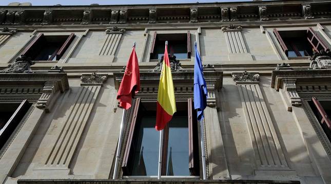 Foto de las banderas de Navarra, España y la Unión Europea, ondeando en la fachada de la sede del Parlamento de Navarra.