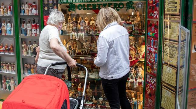Foto de unos clientes observando el escaparate de la tienda de souvenirs Olentzero, situada en la calle Estafeta.