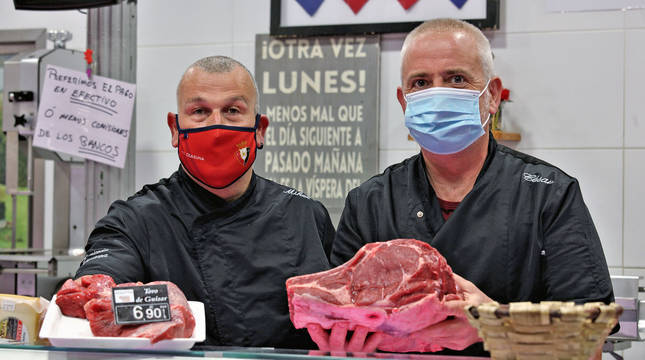 Mikel Aldave y César Salón, de la carnicería Abaurrea, posando ayer con carne de toro en su puesto del mercado de Santo Domingo.