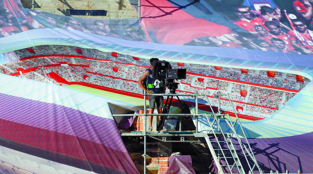 Un cámara de televisión, durante el Osasuna-Getafe, situado en una de las gradas de El Sadar que están tapadas actualmente con lonas que proyectan el estadio reformado y ampliado.