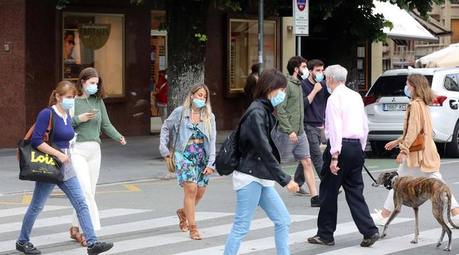 Foto de varias personas que están cruzando un paso de peatones, este miércoles, en el centro de Pamplona, todos con mascarilla.