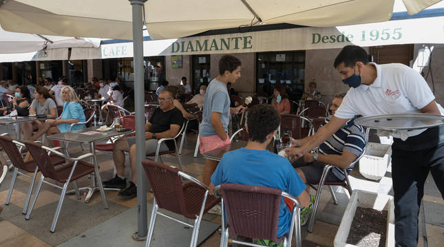 Un camarero sirve a unos clientes en la terraza del bar Diamante de la plaza de los Fueros.