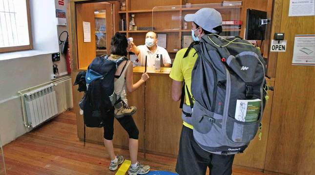 Dos peregrinos se toman la temperatura al entrar en el albergue de Jesús y María, de la calle Compañía de Pamplona.