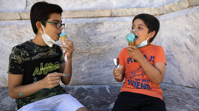 Dos niños disfrutan de un apetecible helado de pitufo también conocido como Blue Ice con virutas de colorines espolvoreadas por encima.