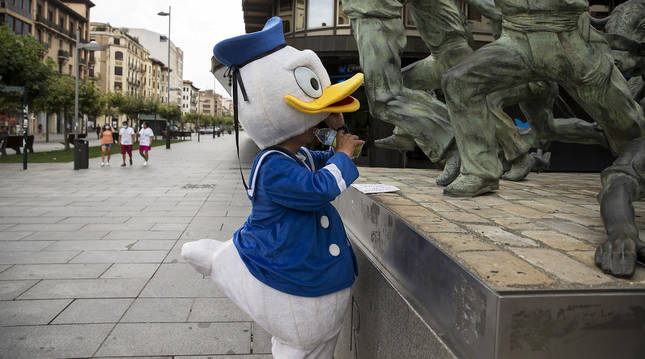 Una persona vestida con el traje de pato Donald se refresca con agua, ayer, en una tarde de 38 grados en Pamplona.