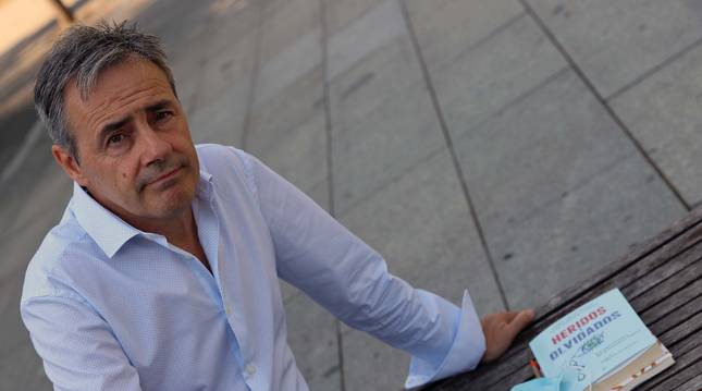 Foto de Tomás Caballero posa con un ejemplar del libro 'Heridos y olvidados' escrito por María Jiménez Ramos y Javier Marrodán Ciordia.