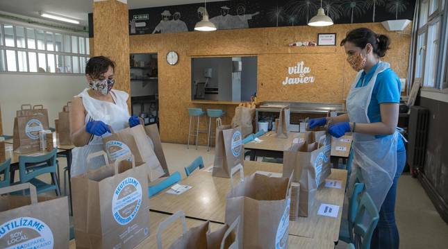 Foto de dos voluntarias preparando las bolsas de comida para los usuarios del servicio de atención a personas desfavorecidas Villa Javier.