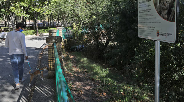 Un viandante pasa por el parque de la Media Luna, junto al letrero colocado por el Ayuntamiento para identificar una colonia controlada.
