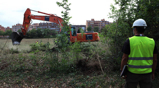 Una máquina trabaja sobre el terreno, en el entorno del Señorío de Eulza. Al fondo, la ronda Cendea de Olza y los últimos pisos de Barañáin.