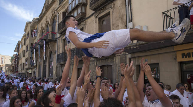 Foto de un joven lanzado al aire por sus amigos en el chupinazo de fiestas de Tafalla de 2019.