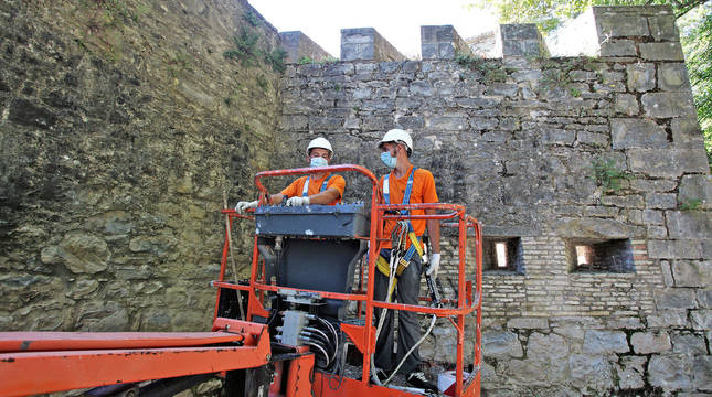 Dos operarios de Leache mueven el vehículo para retirar las malas hierbas de las cañoneras y merlones del fortín de San Bartolomé.