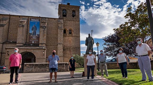 Algunos de los socios de la cofradía Amigos de San Veremundo en la entrada de la parroquia, junto con la estatua del patrón de la localidad.