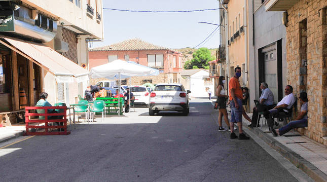 Varios vecinos congregados a la sombra enfrente del bar de Murillo que se hubiese disparado el chupinazo de la localidad.