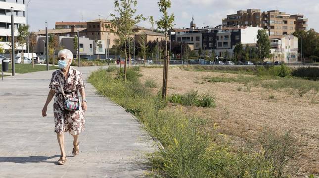 Foto de una mujer junto a la zona del parque que se ha secado, a la derecha de la imagen.