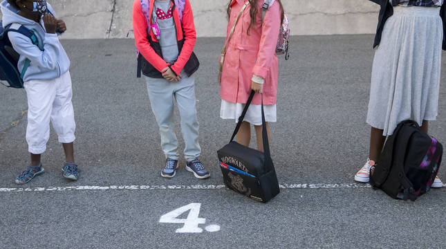 Foto de escolares con sus mochilas en un patio.