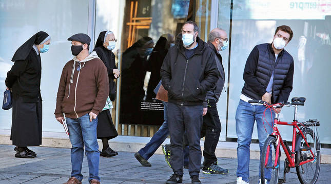 Un grupo de personas con mascarillas y guardando las distancias en la Plaza de Merindades de Pamplona.