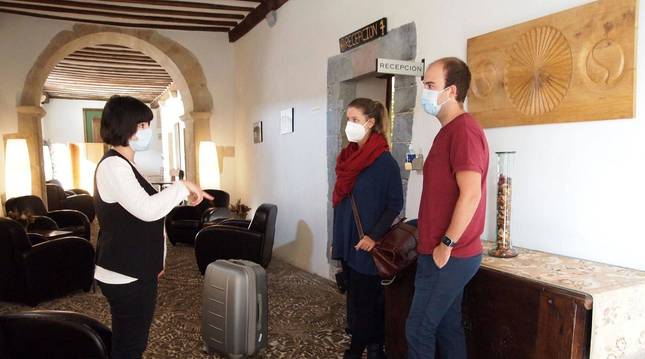 Edurne Vidador Barberena, recepcionista del Hotel Roncesvalles, atiende a dos turistas de Barcelona