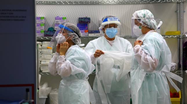Foto del pasado abril, de tres sanitarias de la UCI del Complejo Hospitalario de Navarra, colocándose el equipo de protección.