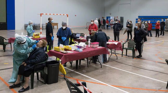Una vecina se somete a la prueba PCR en el polideportivo, mientras otros cadreitanos esperan su turno para realizársela.