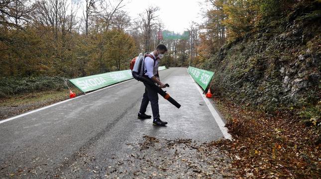 Una persona retira las hojas caídas en las últimas horas en la carretera de San Miguel de Aralar, por donde discurre la segunda etapa de la Vuelta.