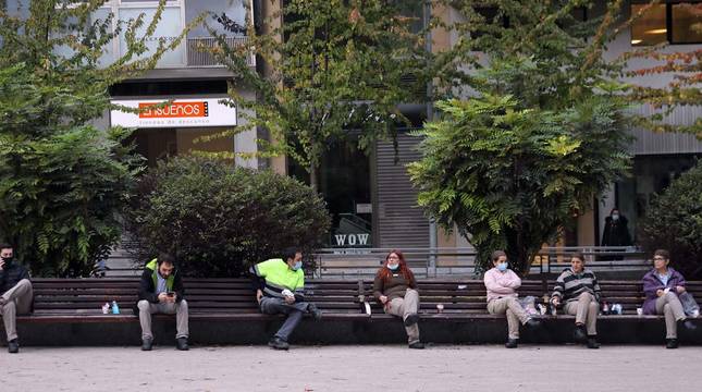 La plaza del Vínculo de Pamplona, con trabajadores y viandantes sentados en el banco para tomar un café o almorzar.