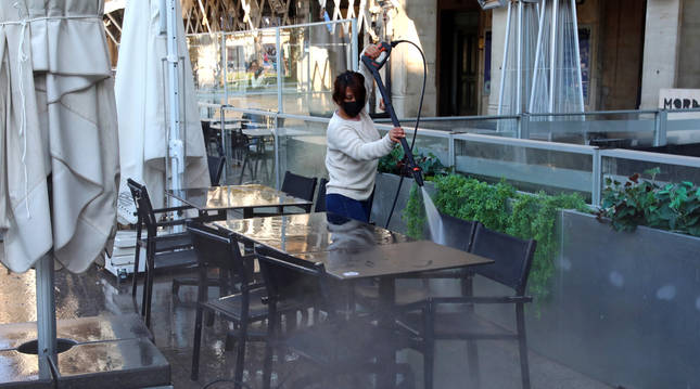 Foto de una trabajadora limpiando las terrazas que se reabrirán a partir de este jueves.