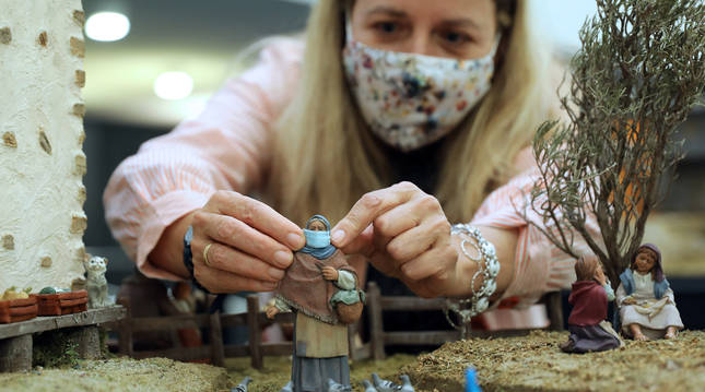 Ana Estrella Ramírez Avizanda coloca una mascarilla a una de las figuritas del belén que recrea el caserío más antiguo de Guipúzcoa.
