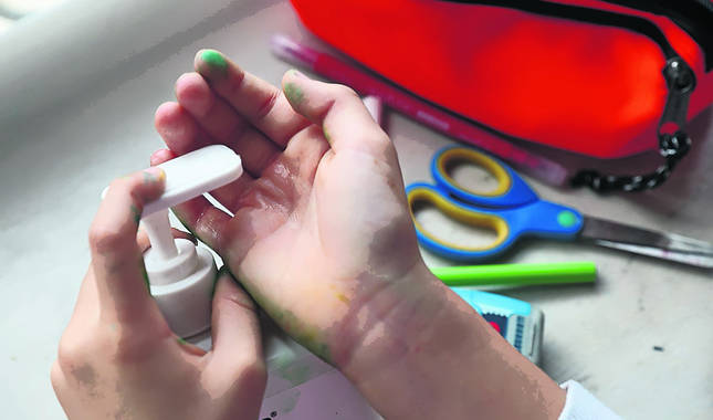 Un niño vierte gel hidroalchólico en la palma de su mano, después de hacer manualidades.
