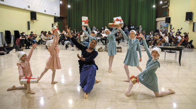 Foto de Galina Rodríguez (centro y agachada) junto al grupo de teatro infantil durante el ensayo del domingo en el Colegio Luis Amigó de Mutilva. Al fondo, la Sinfonietta de Pamplona.