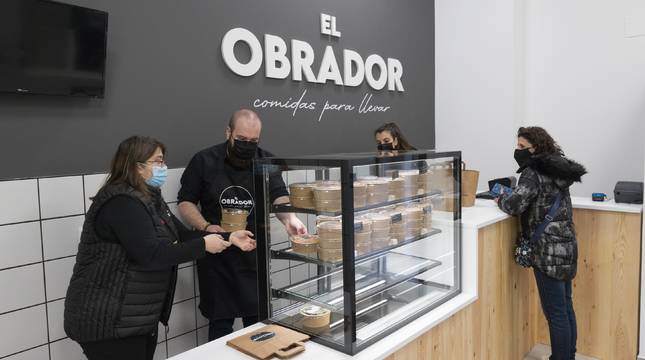 EL OBRADOR, DE LA COCINA A CASA Arriba, una trabajadora del Obrador revisa un guiso con la cocinera, Lourdes Arilla, al fondo. En la foto de abajo, una clienta recogiendo su comida.