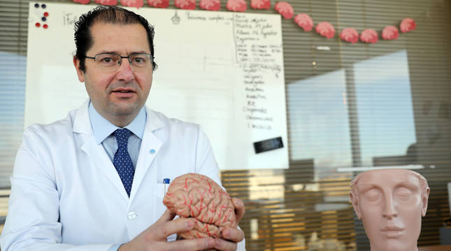 Foto de Pablo Irimia, gallego de 49 años, posa con la figura de un cerebro en su consulta de neruología de la CUN.