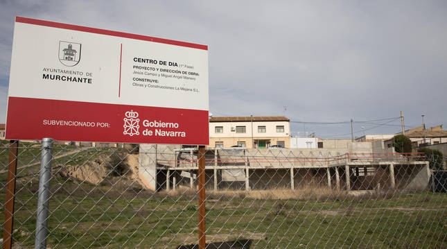 Foto del cartel que anuncia la construcción del centro de día, con la estructura que se hizo del edificio, detrás