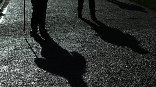 La sombra de dos personas mayores que están paseando por Pamplona se proyecta sobre la acera.