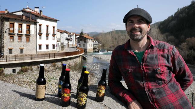 Jox Ubau Galarza, en el puente de Burgui, con la cerveza que elaboran en el pueblo.