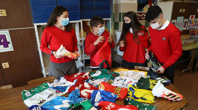 Foto de algunos de los alumnos encargados de llevar a cabo el proyecto miran el material deportivo que será sorteado.