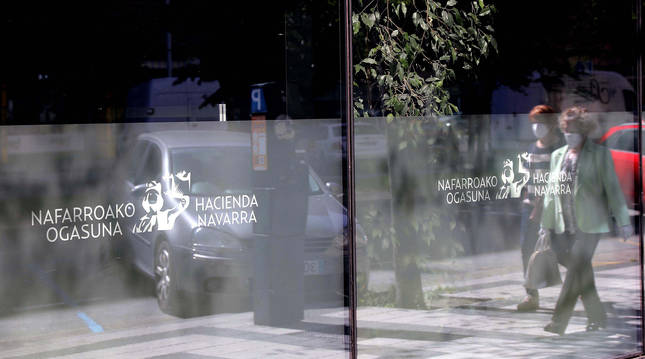 Foto de dos personas reflejadas en el cristal de la oficina de Hacienda en la calle Esquiroz de Pamplona.