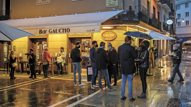 Viandantes y clientes tomando algo en la terraza del bar Gaucho, en Pamplona, en la lluviosa noche del pasado jueves.