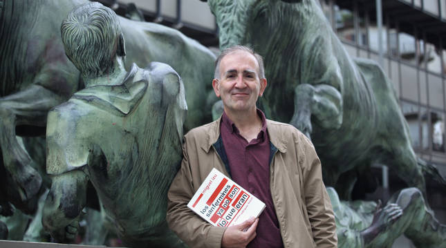 Miguel Izu posa con su último libro en el monumento al Encierro, en la avenida de Roncesvalles.