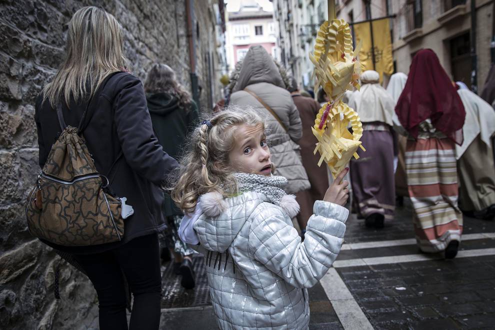 Una niña carga con una hoja de palma durante la procesión.