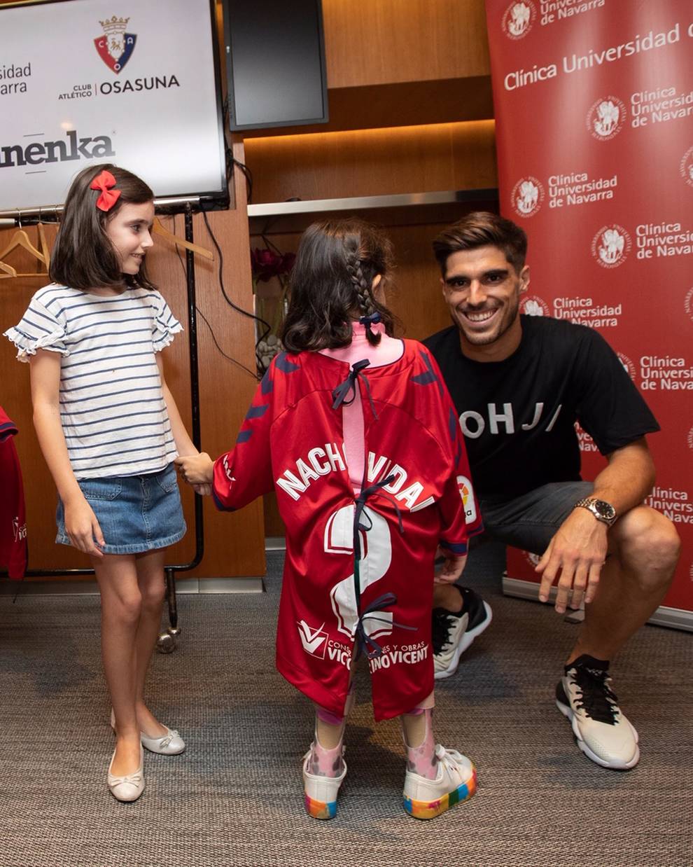 El jugador del C.A. Osasuna Nacho Vidal hace entrega de su camiseta convertida en bata a una niña ingresada.