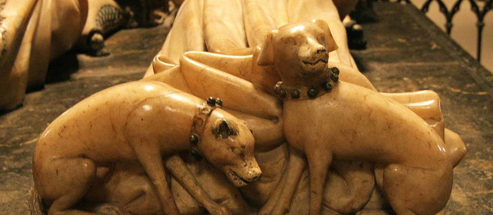 Foto de la pareja de lebreles a los pies de la reina Leonor en el sepulcro de Carlos III en la catedral de Pamplona, obra de Jehan de Lome, 1413-1419.